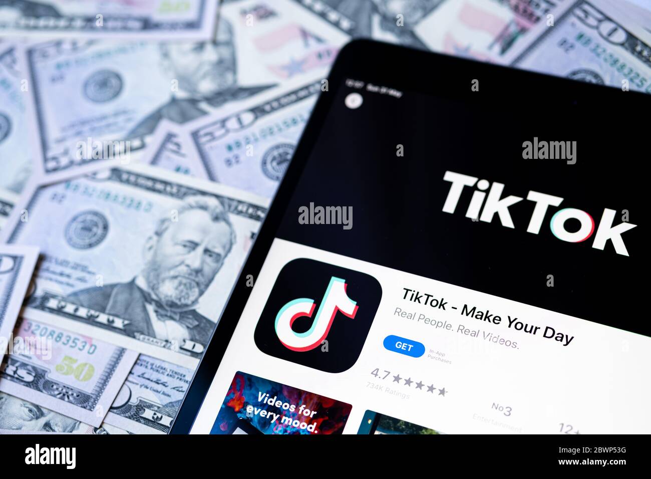 Stone, Staffordshire / UK - 28 maggio 2020: App TikTok nell'app store Apple sullo schermo dell'ipad e bollette in dollari USA accanto ad essa. Messa a fuoco selettiva. Concettuale Foto Stock