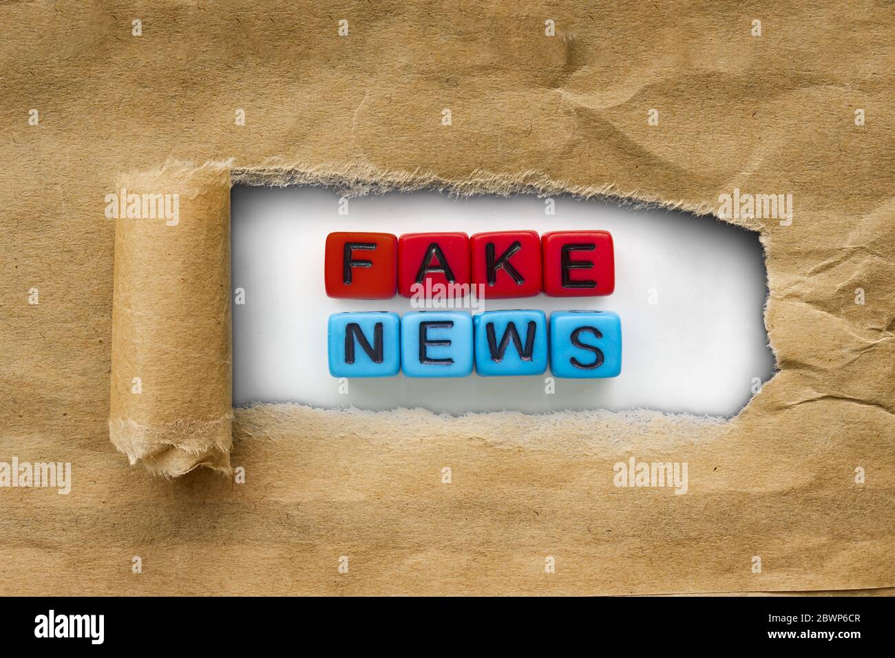 Marrone pacchetto kraft carta strappata per rivelare i cubi rosso e blu con le parole: Notizie false. Novità sui prodotti concept Foto Stock