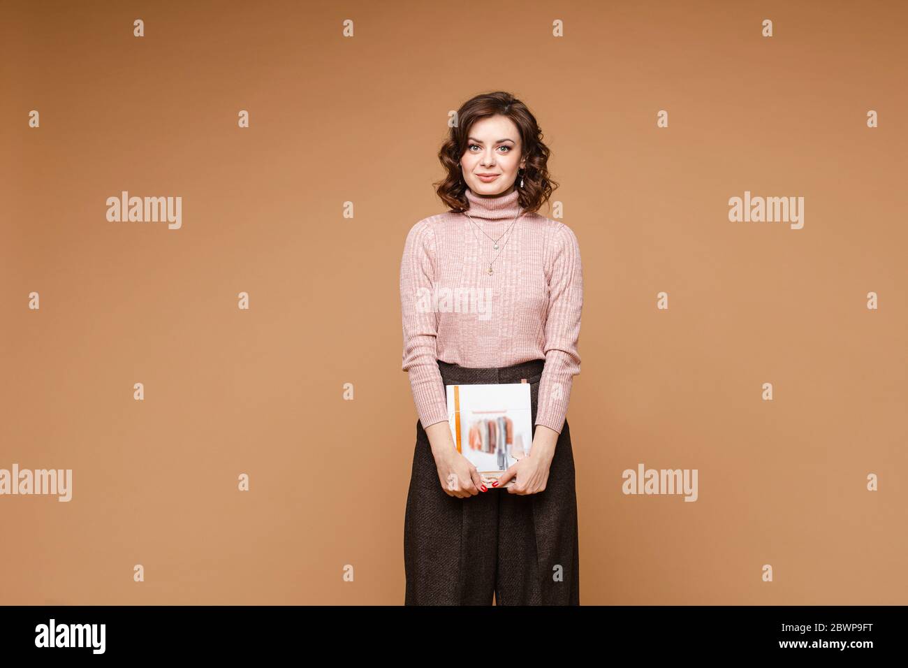 Stilista professionale con un libro a mani. Pantaloni marrone scuro con un  libro Foto stock - Alamy