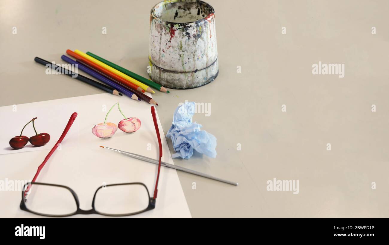 attrezzature per arti visive per la dimostrazione in classe da parte dell'insegnante. Le vernici acquose pennellano carta e matite su una scrivania o un tavolo nella sala d'arte Foto Stock