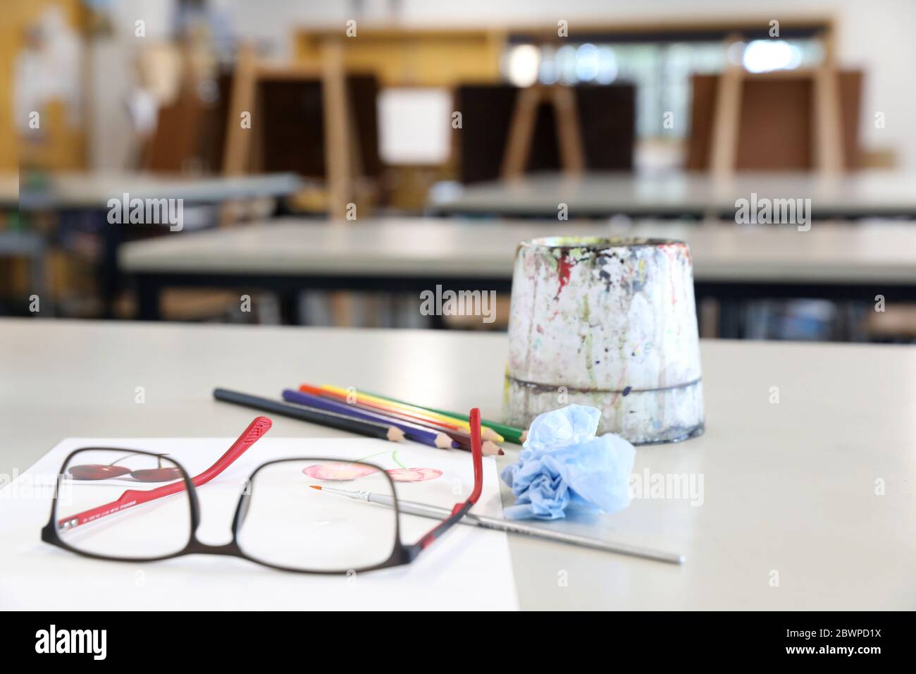 attrezzature per arti visive per la dimostrazione in classe da parte dell'insegnante. Le vernici acquose pennellano carta e matite su una scrivania o un tavolo nella sala d'arte Foto Stock