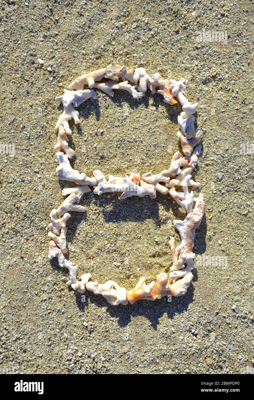 Il numero otto (8) è stato disposto in piccoli pezzi di corallo bianco imbianchito dal sole su una spiaggia sull'isola della Grande barriera Corallina di Heron. Foto Stock