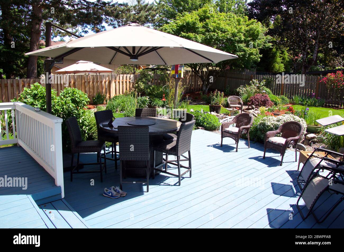 Giardino sul retro con terrazza, sedie e tavolo con ombrellone Foto Stock