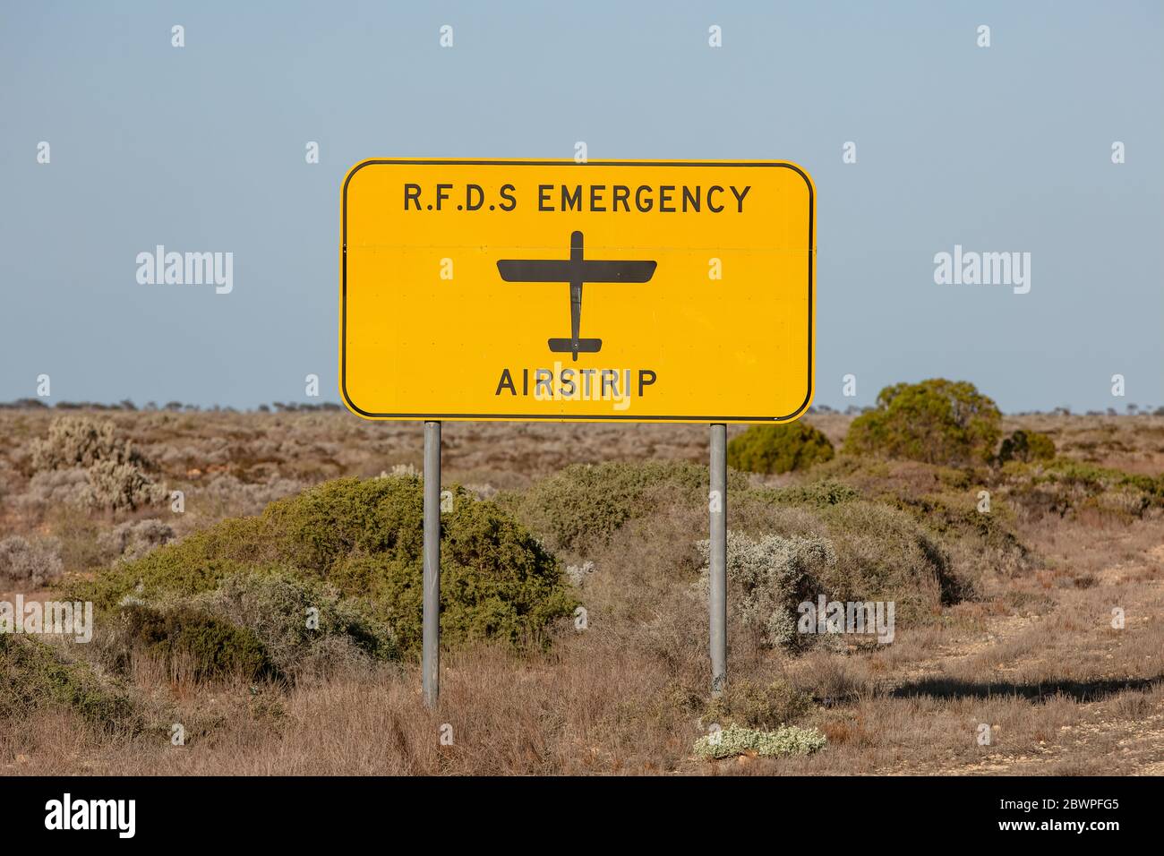 Il segnale Royal Flying Doctor Emergency Service che indica la strada può essere utilizzato anche come striscia di atterraggio in un'emergenza medica. Catturato in Australia Occidentale Foto Stock