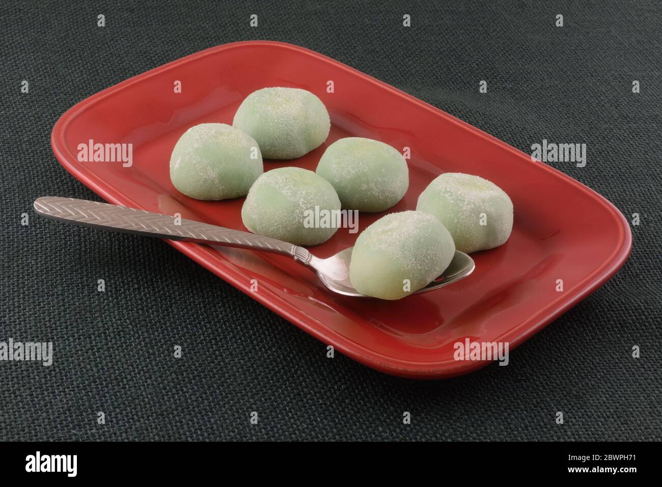 Palle di gelato al tè verde mochi su piatto rosso con cucchiaio da portata Foto Stock