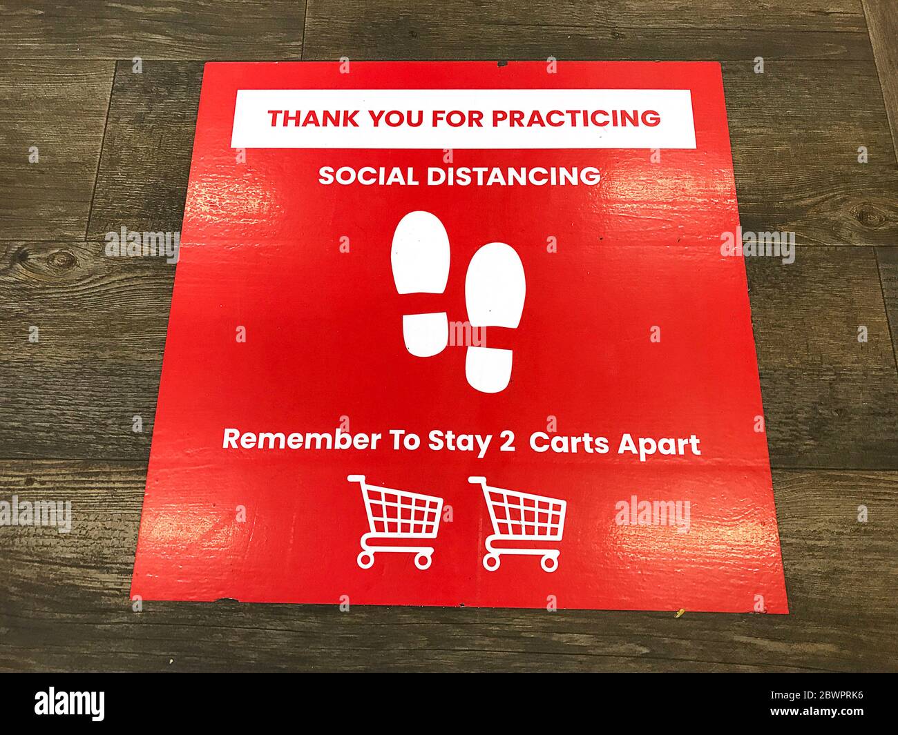 Cartello di allontanamento sociale sul pavimento del negozio di alimentari che chiede ai clienti di praticare a una distanza di 6 piedi utilizzando il carrello come riferimento per prevenire Foto Stock