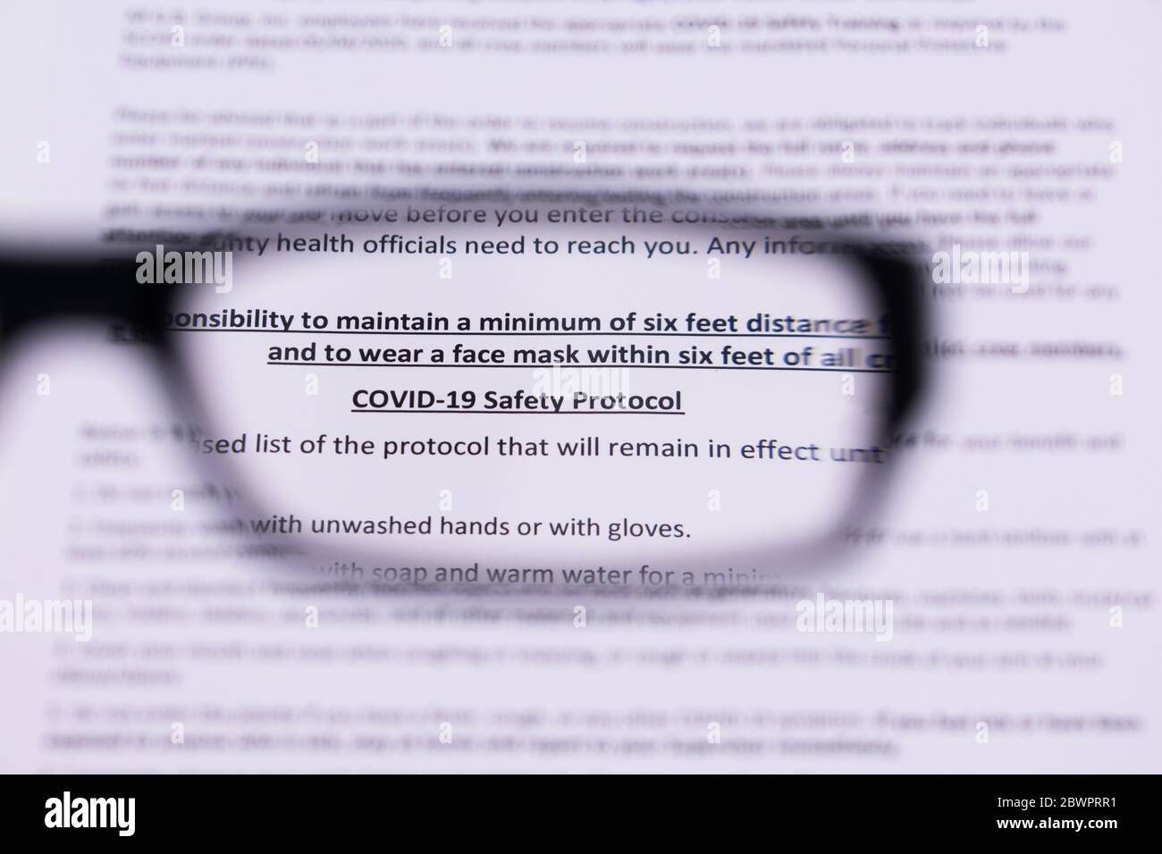 Testo del protocollo di sicurezza Covid-19 visto attraverso gli occhiali da lettura. Messa a fuoco selettiva. Foto Stock