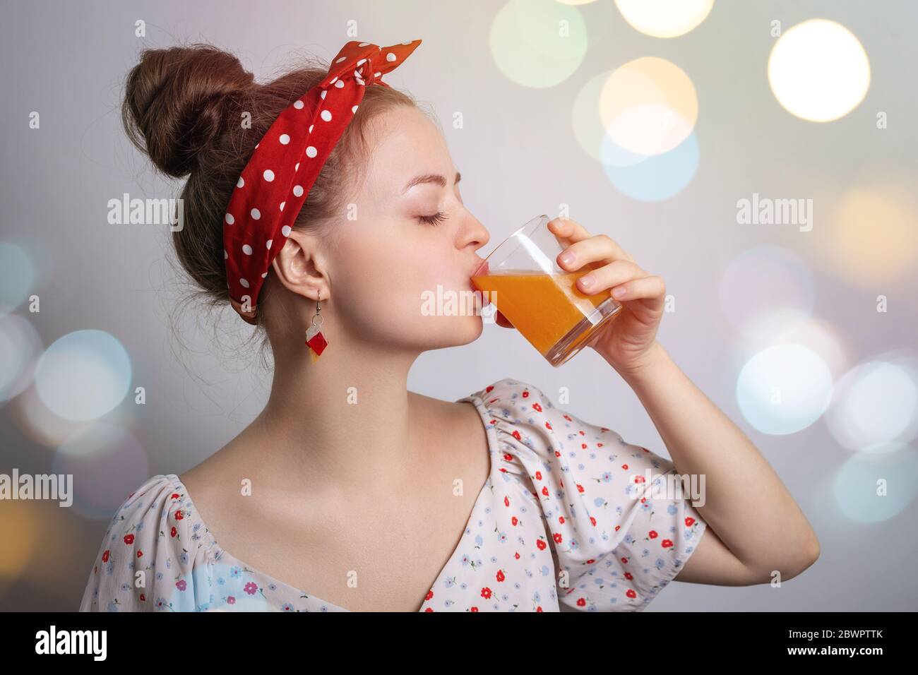 Giovane donna caucasica ragazza che beve un bicchiere di succo di frutta o di mango o di arancia o cocktail. Fresco concetto di festa estiva Foto Stock