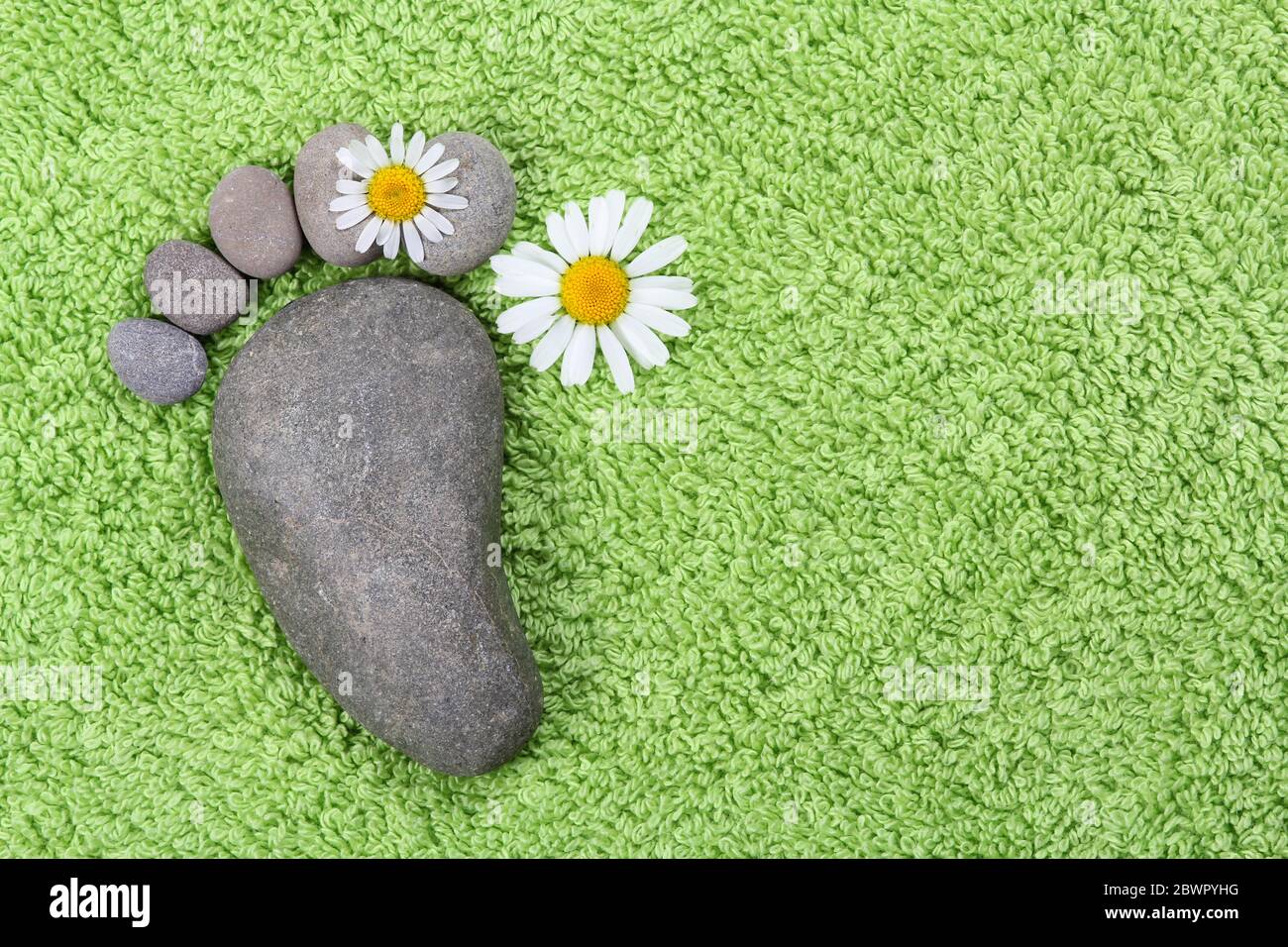 Piede con camomilla su asciugamano verde Foto Stock