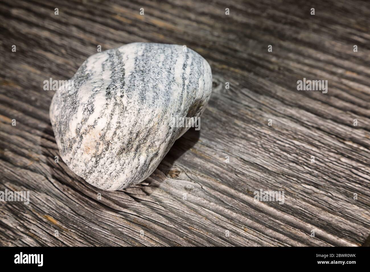 pietra isolata con strisce su legno Foto Stock