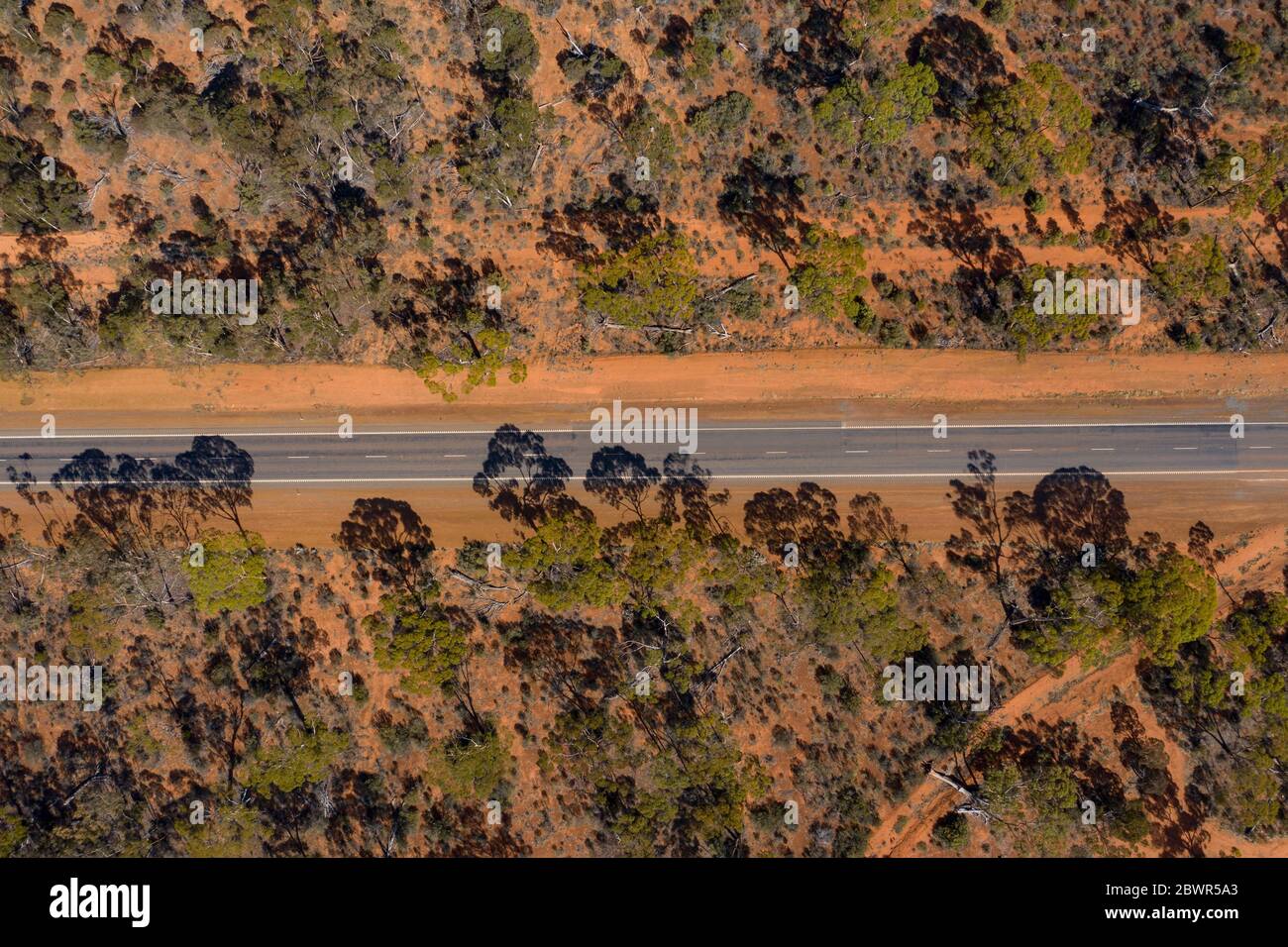 Vista aerea di una lunga strada diritta nell'entroterra australiano desertato rosso nell'Australia occidentale Foto Stock