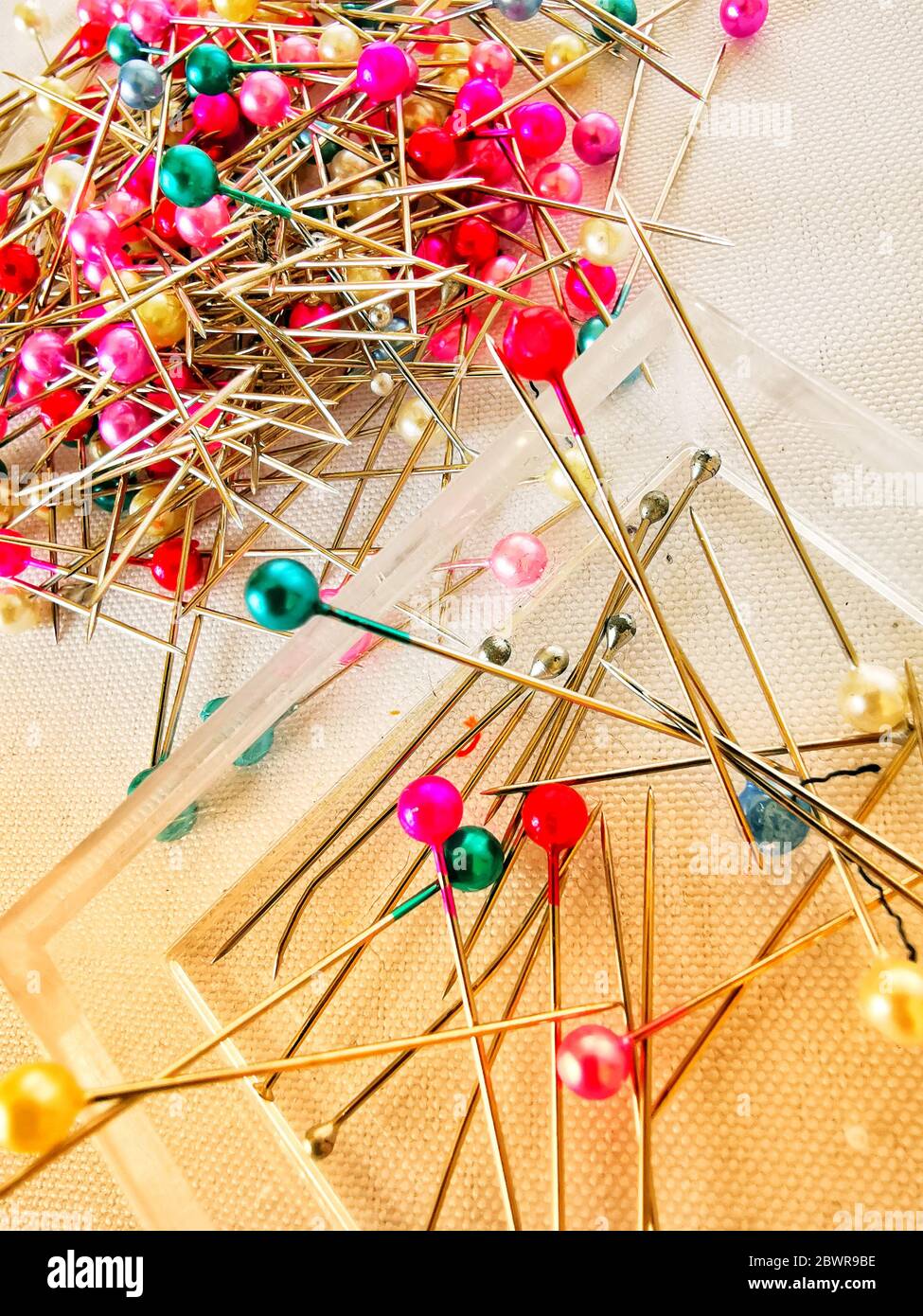 Scatto ad angolo elevato di spilli colorati per cucire su un tessuto bianco Foto Stock