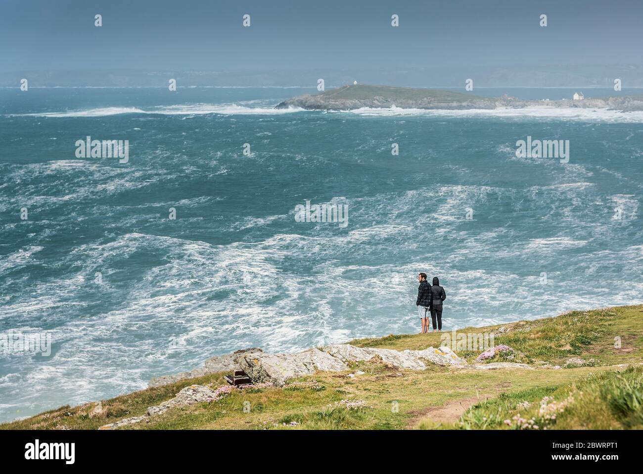 La gente gode della vista spettacolare attraverso la baia di Fistral verso Towan Head in una giornata ventosa a Newquay in Cornovaglia. Foto Stock