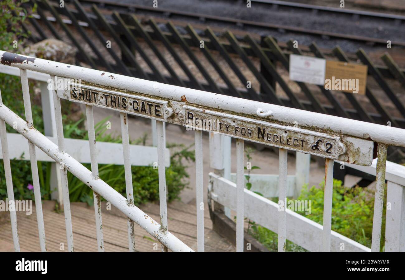 Chiudi questo cartello di avvertenza su un cancello bianco a Goathland sulla North York Moors Railway - penalità per negligenza £2 Foto Stock