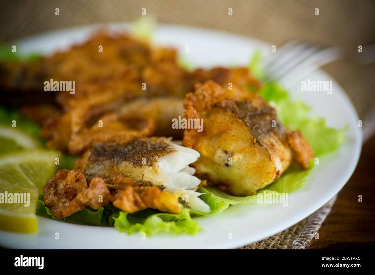 pesce di nasello fritto in pastella con lattuga e limone in un piatto Foto Stock