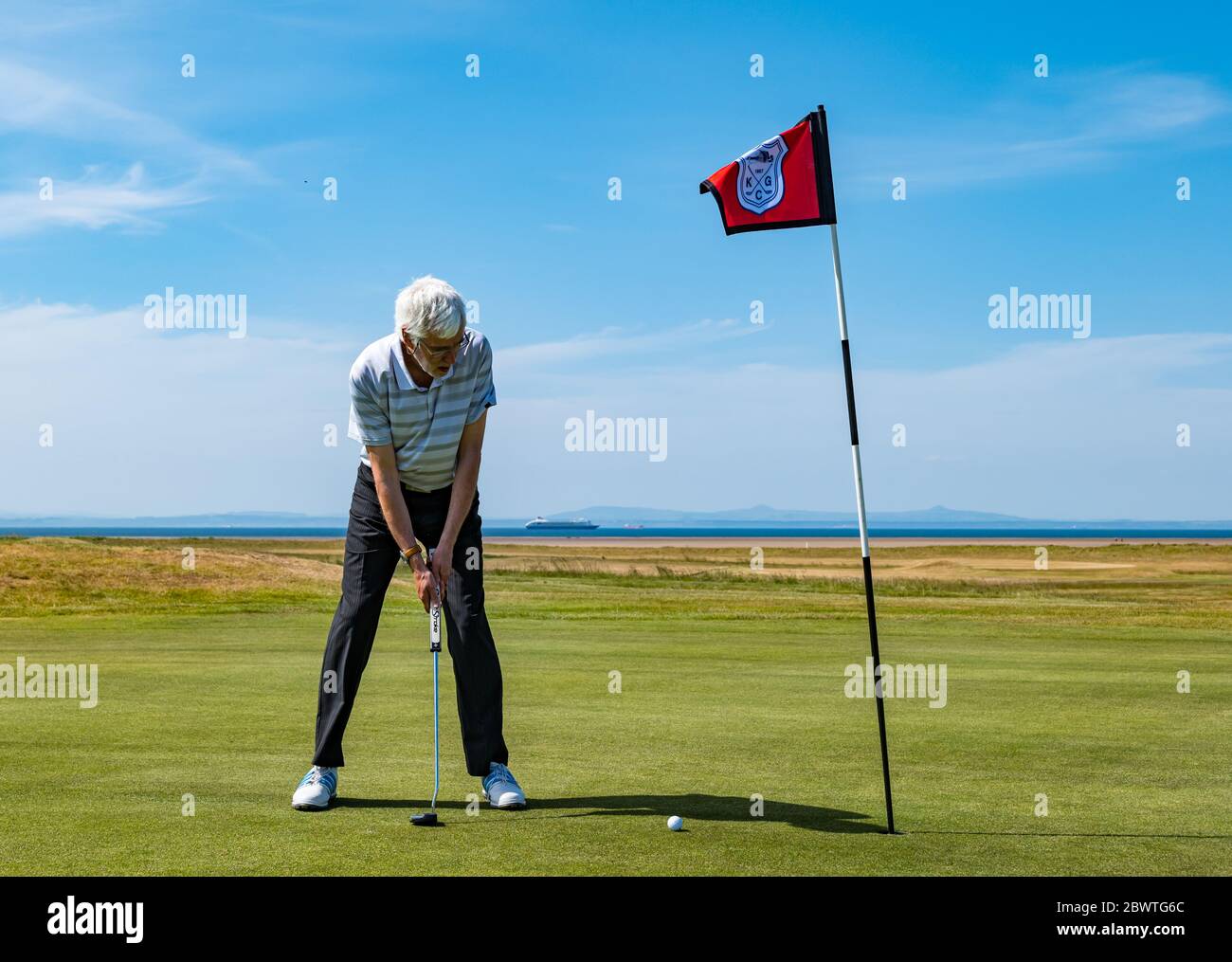 Dr Mike Mitchell. Capitano del club, colpendo la palla di golf su putting green, Kilspindie Golf Club, Aberlady, Scozia, Regno Unito Foto Stock