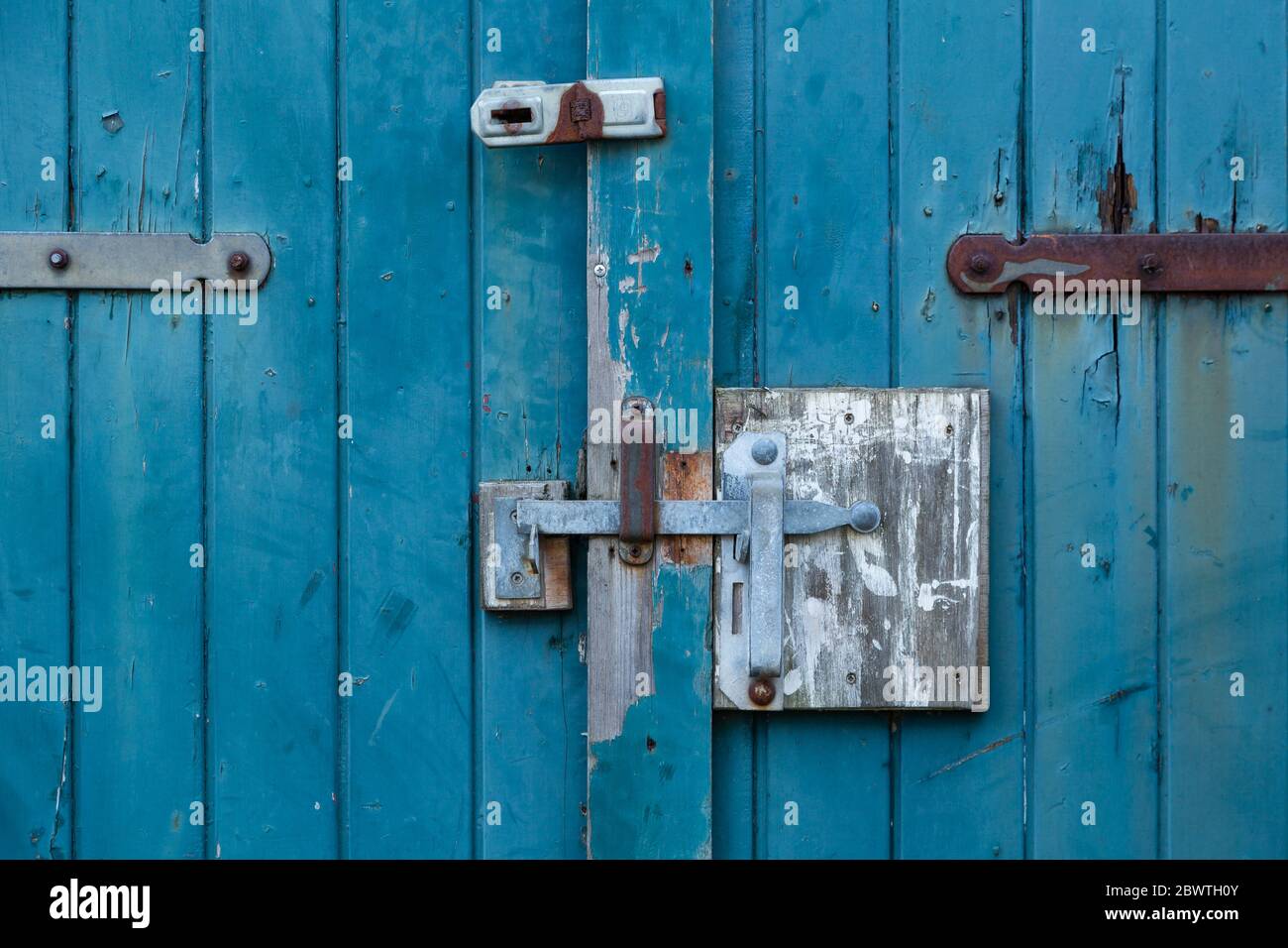chiusura e lucchetto sulla vecchia porta in legno con vernice turqoise Foto Stock