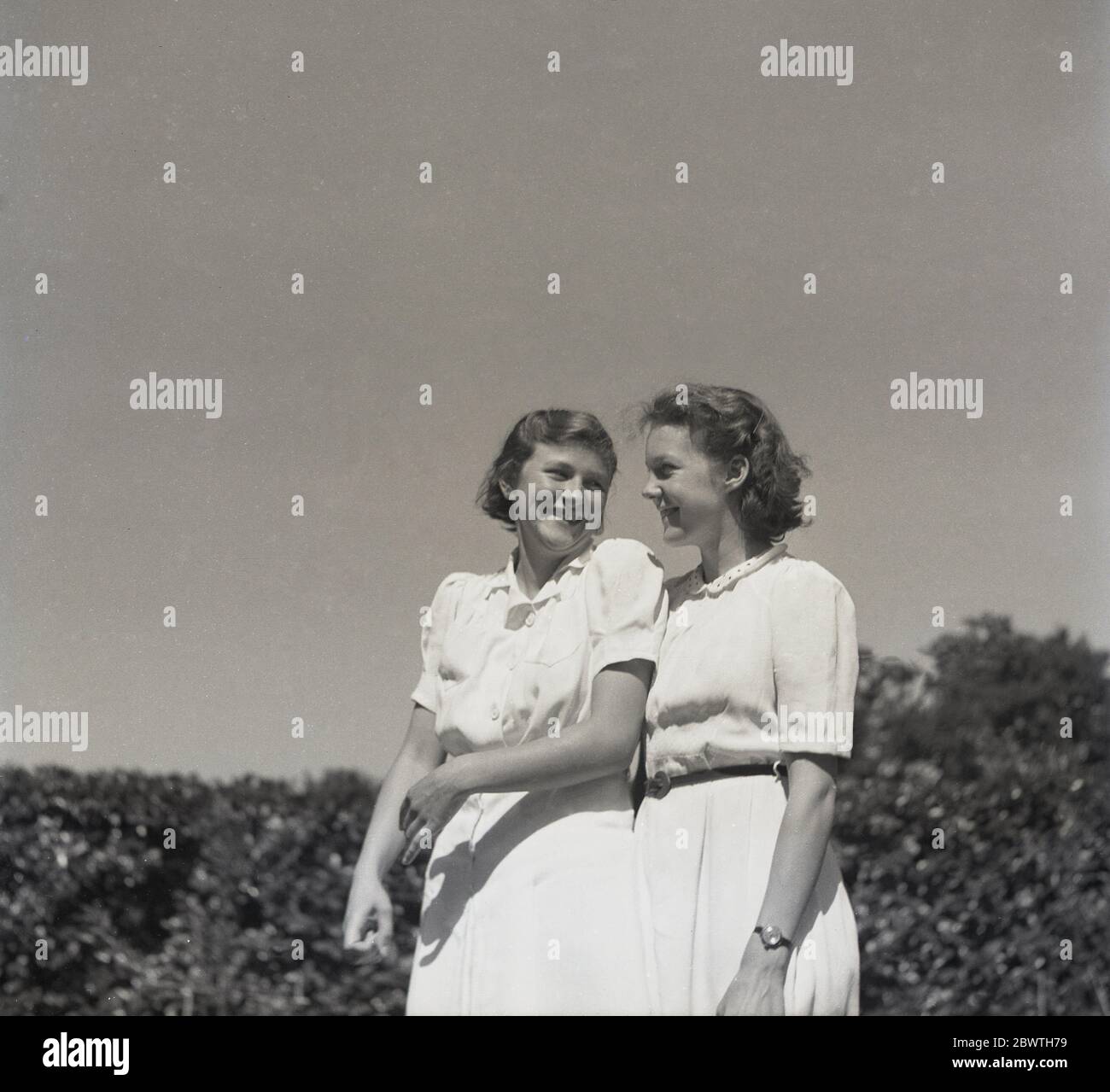 Anni 60, storica, al sole fuori, una madre che si trova vicino e guarda con orgoglio e amore a una giovane donna, sua figlia, Inghilterra, Regno Unito. Foto Stock