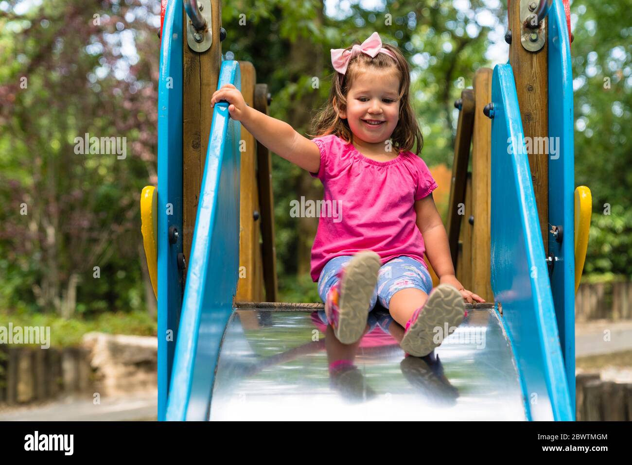Ritratto di una bambina sorridente sullo scivolo del parco giochi Foto Stock