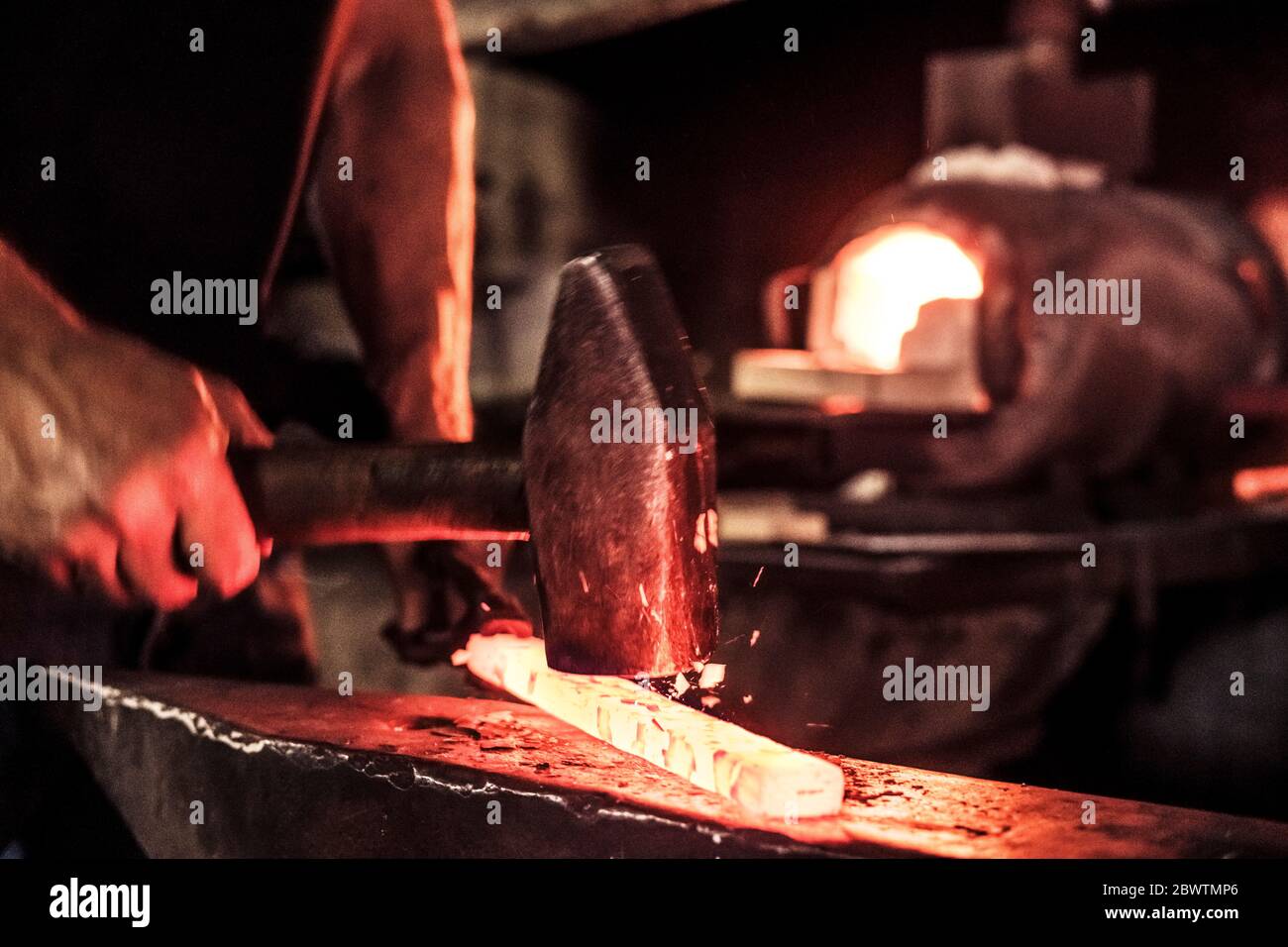 Coltello in lavoro, schegge d'acciaio durante il martellamento dell'acciaio Damasco Foto Stock