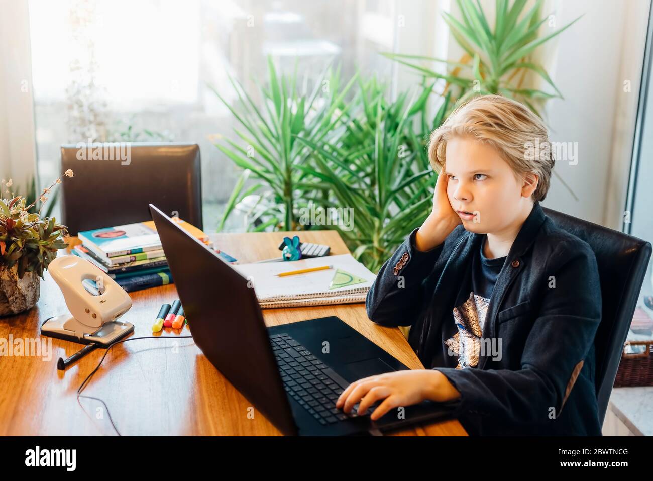 Ragazzo frustrato seduto alla scrivania con un computer portatile Foto Stock