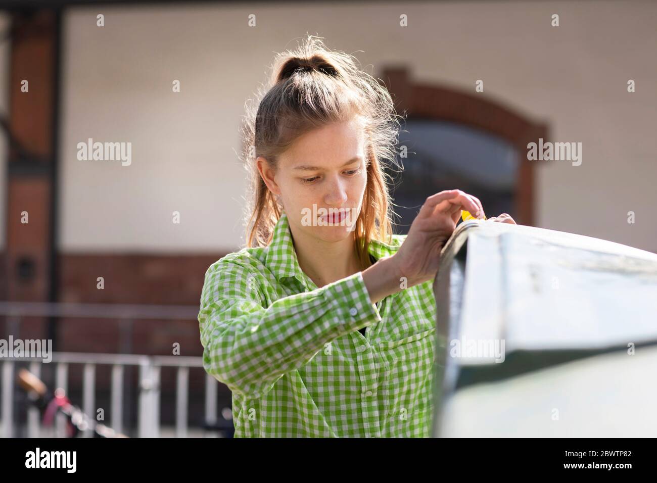 Giovane donna che getta rifiuti nel cestino di riciclaggio Foto Stock