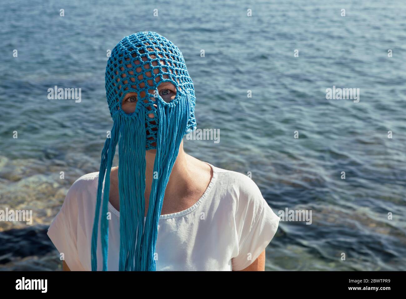 Ritratto di donna che indossa un ricchino blu con frange di fronte al mare Foto Stock