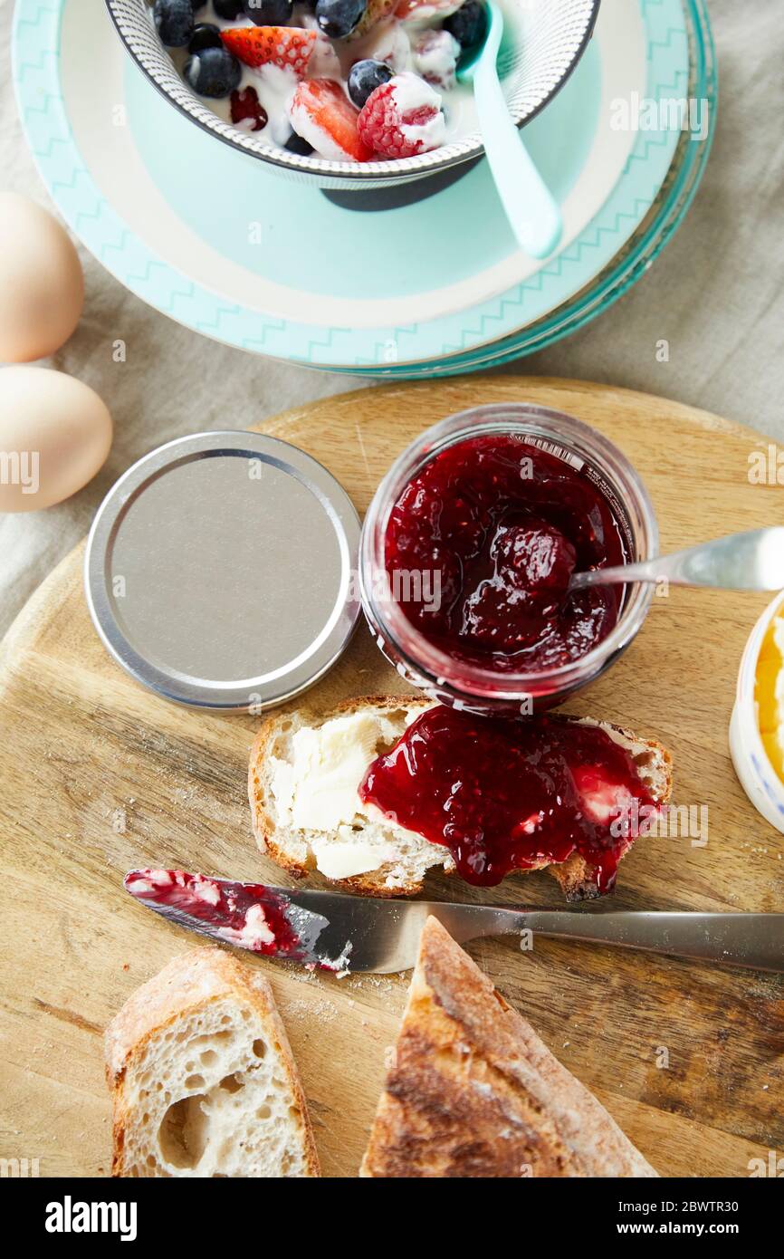 Pane con marmellata e ciotola di muesli di frutta sul tavolo della colazione Foto Stock