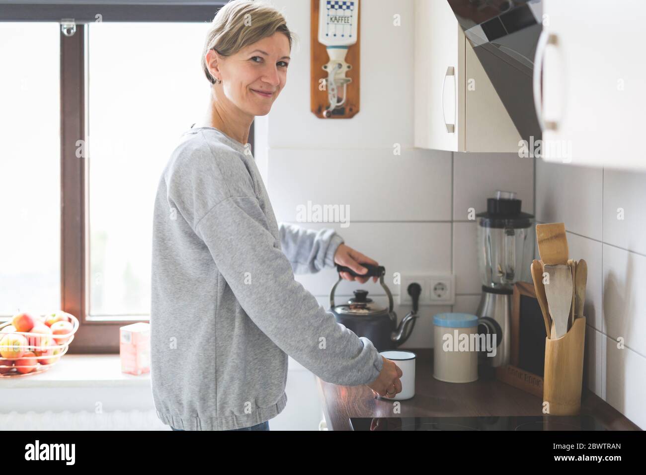Donna matura che prepara il tè in cucina Foto Stock
