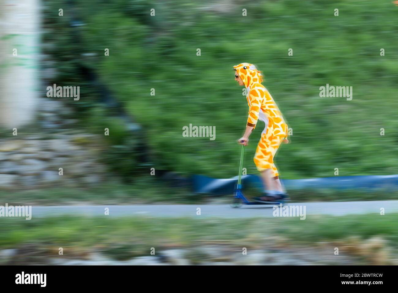 Giovane uomo che indossa costume da giraffa su scooter Foto Stock