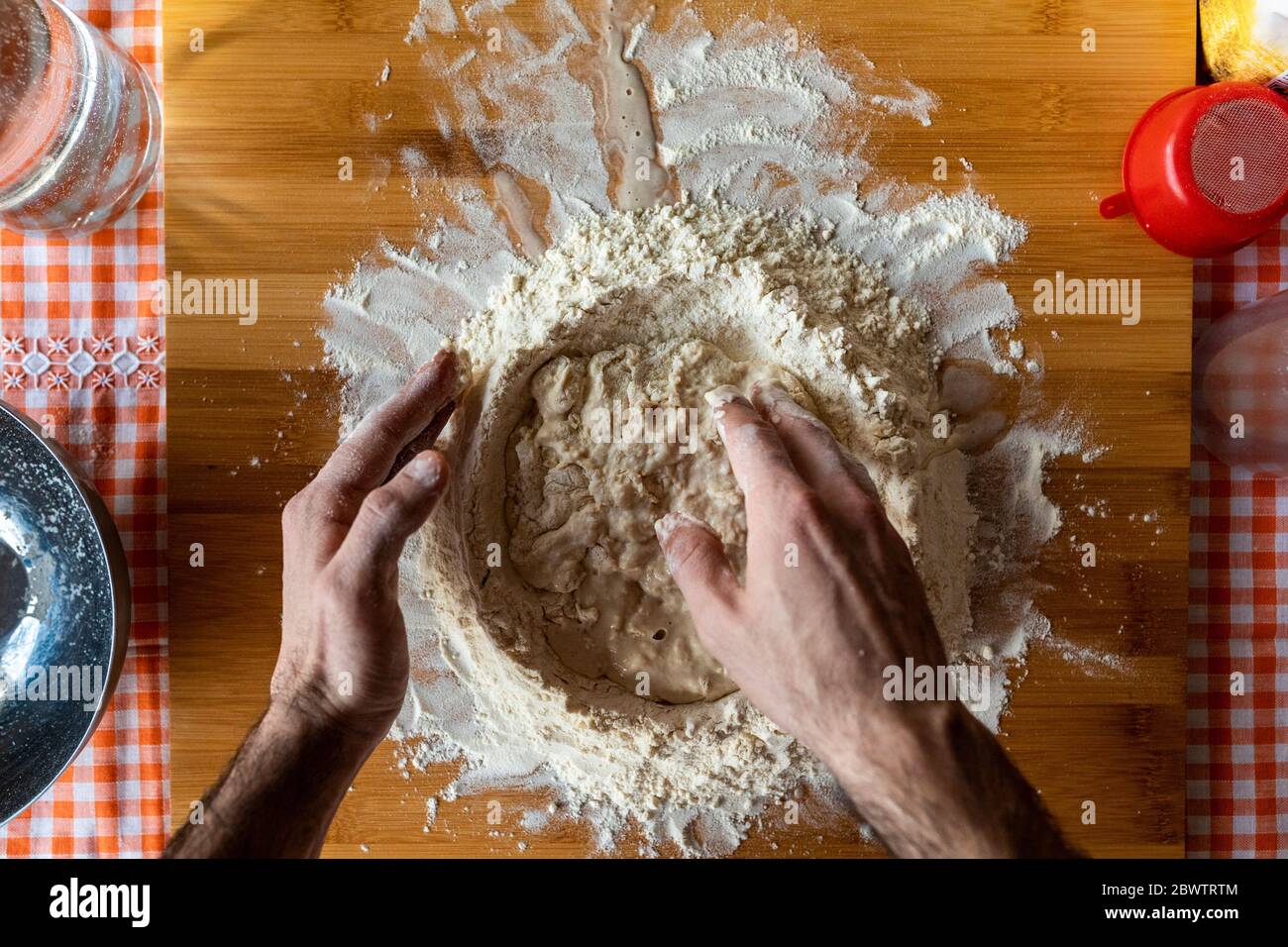 Mani dell'uomo che preparano l'impasto su tavola di legno, vista dall'alto Foto Stock