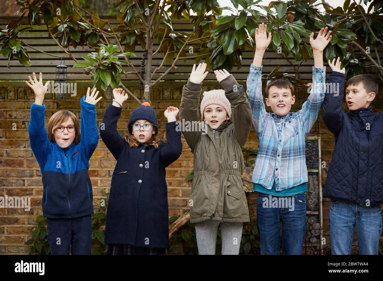 Gruppo di bambini che si alzano le braccia durante il periodo di pausa Foto Stock