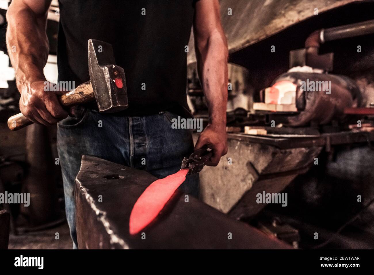 Coltello in lavoro, schegge d'acciaio durante il martellamento dell'acciaio Damasco Foto Stock