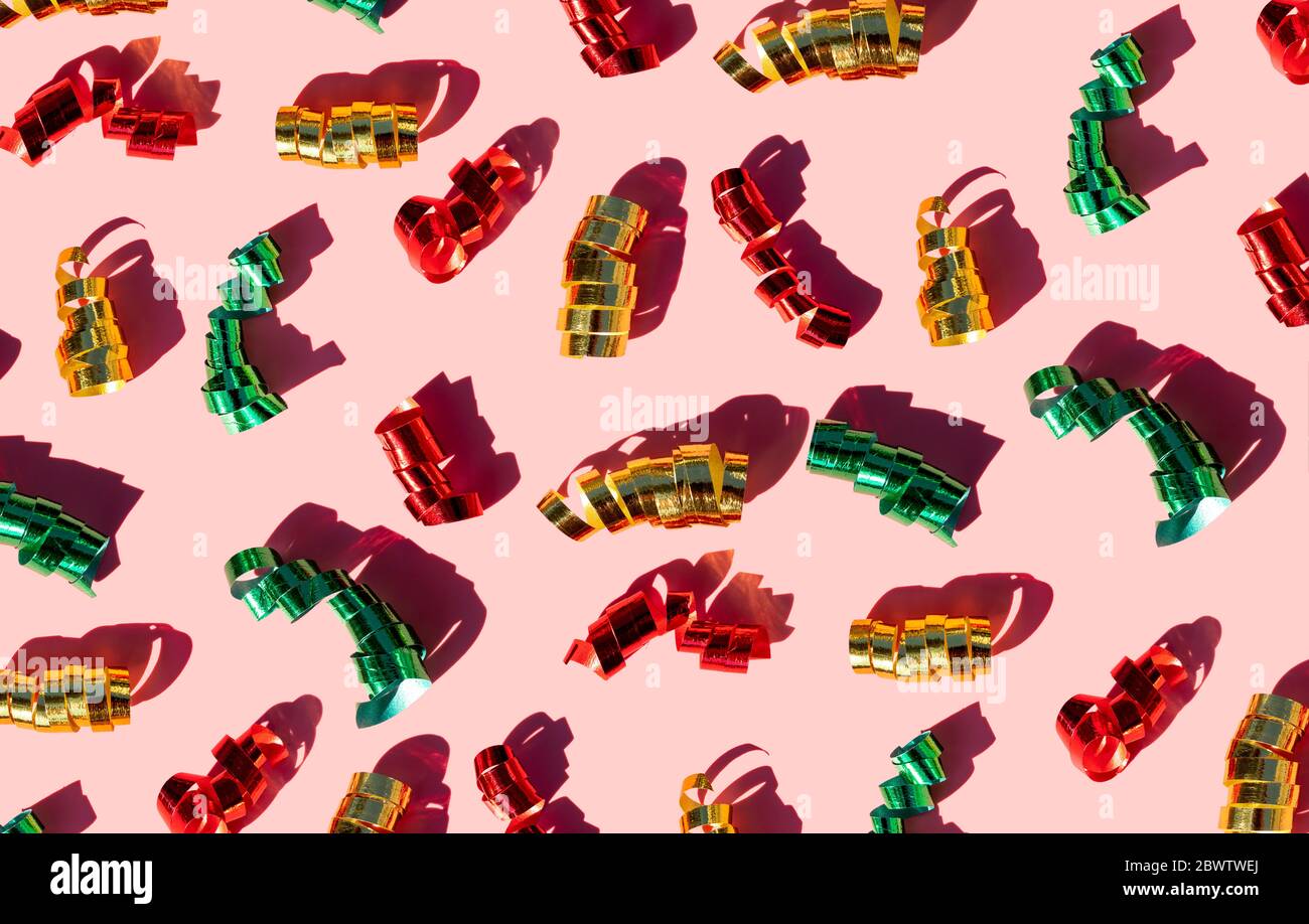 Nastri di confetti lucidi su sfondo rosa pastello Foto Stock