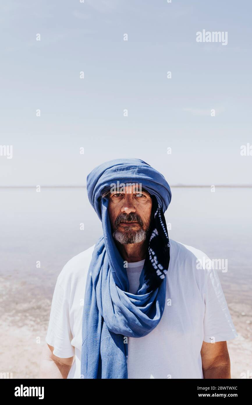 Uomo nel deserto di Merzouga che si trova di fronte al lago, Marocco Foto Stock