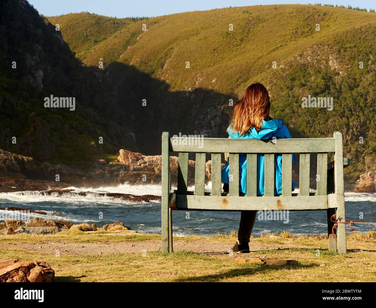 Donna seduta su una panchina che ammira il panorama, Tsitsikamma National Park, Sudafrica Foto Stock