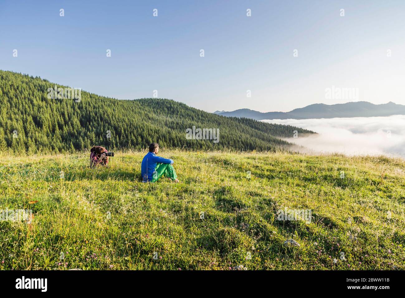 Uomo e donna con macchina fotografica su un prato in montagna, Achenkirch, Austria Foto Stock