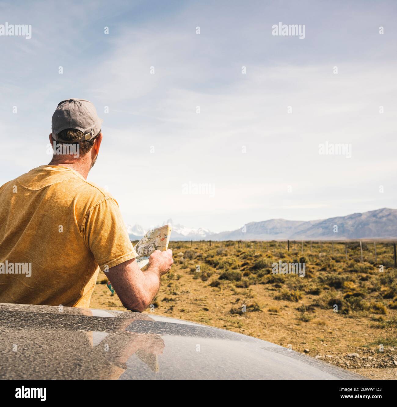 Vista posteriore dell'uomo con mappa in auto in un paesaggio remoto a Patagonia, Argentina Foto Stock