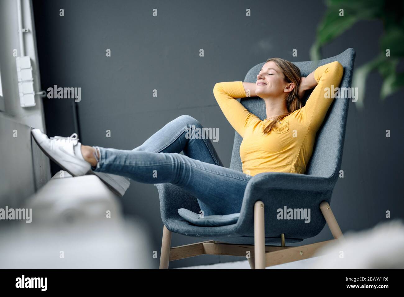 Giovane donna sorridente che si rilassa in poltrona Foto Stock