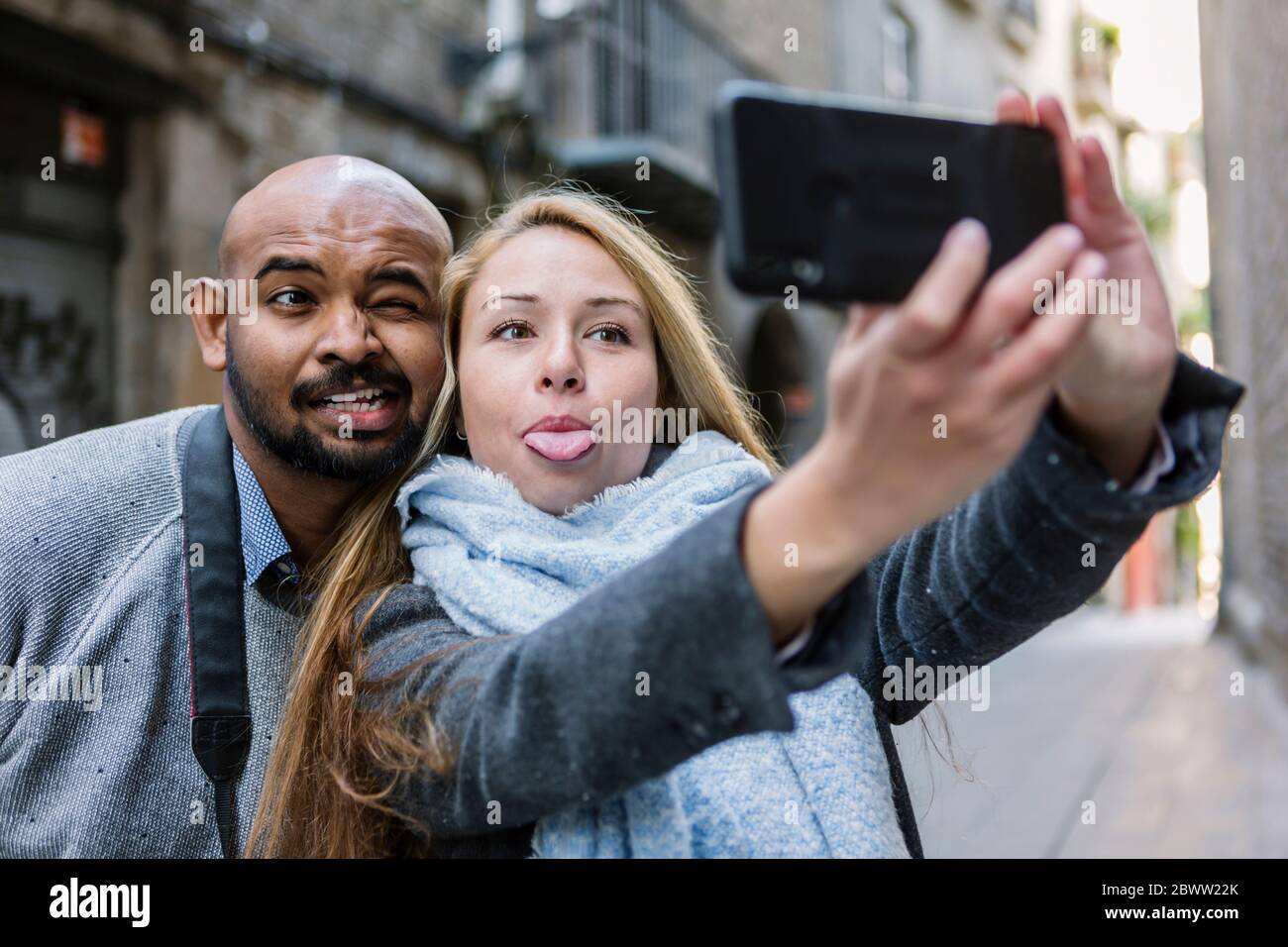 Ritratto di volti coupling mentre si prende selfie con smartphone, Barcellona, Spagna Foto Stock
