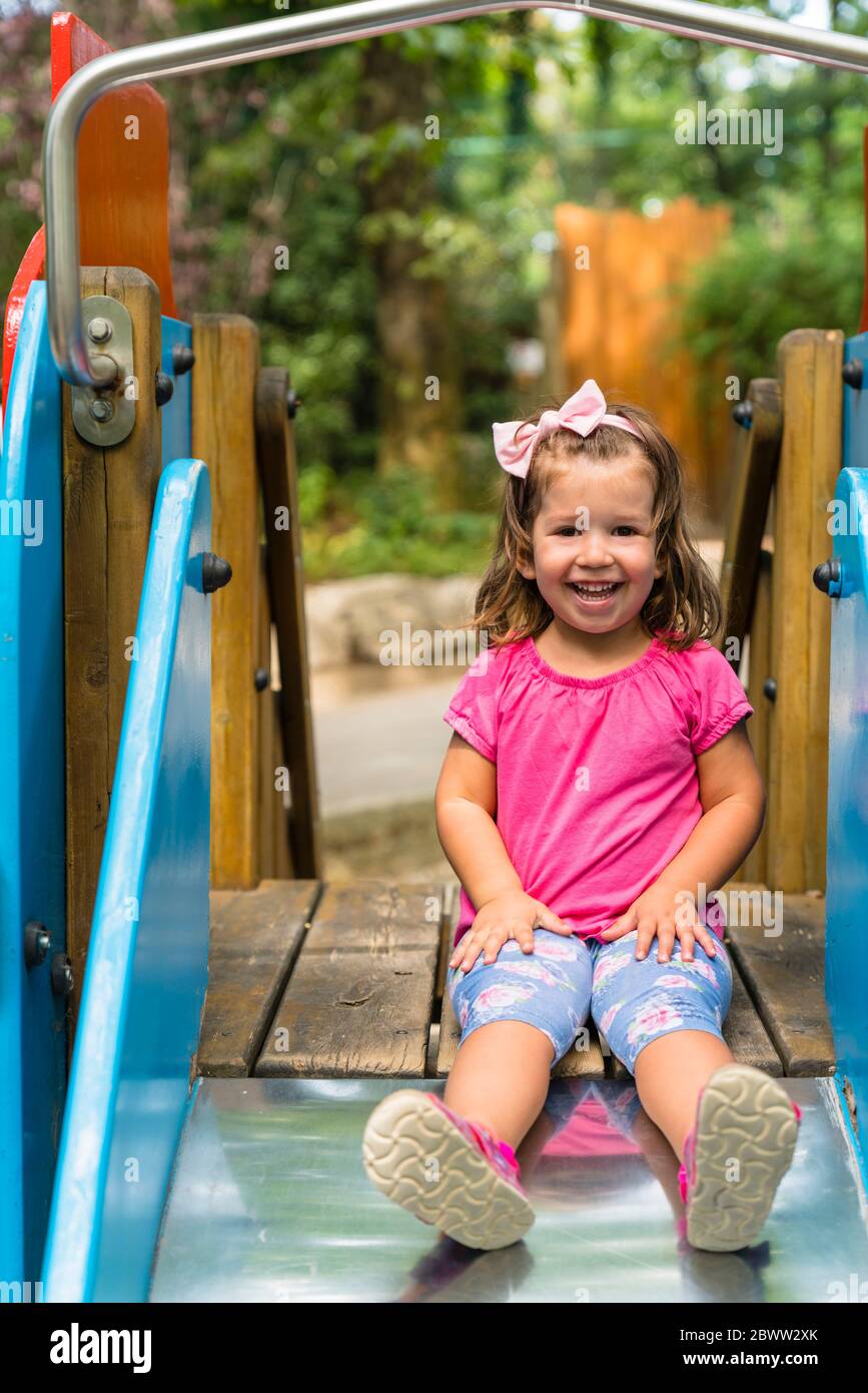 Ritratto di felice bambina seduta su scivolo giochi Foto Stock