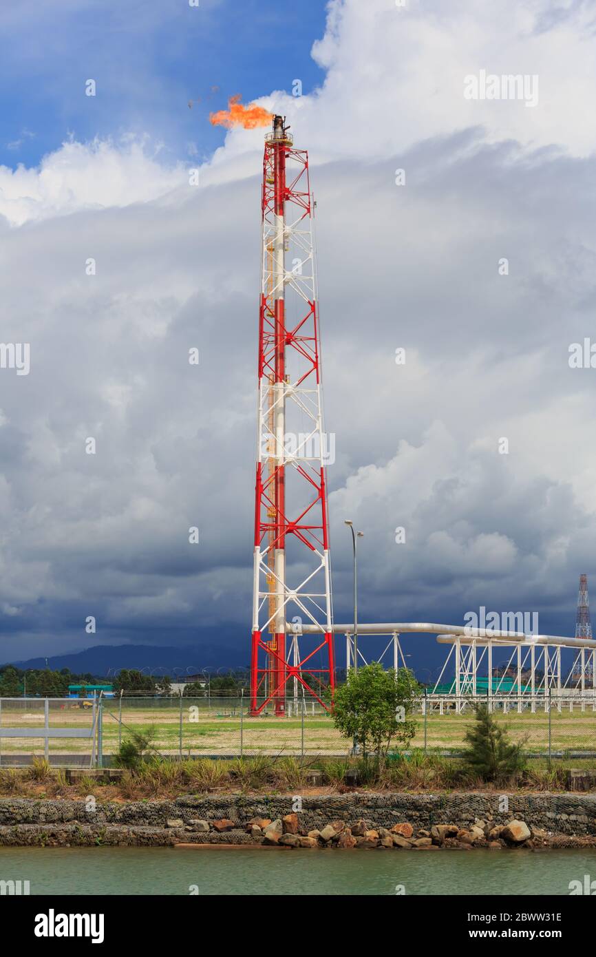 Catasta di svasatura dipinta di rosso e bianco di un impianto petrolchimico  a Kimanis, Sabah, Malesia, con un cielo drammatico sulla catena montuosa  dei Crocker Foto stock - Alamy