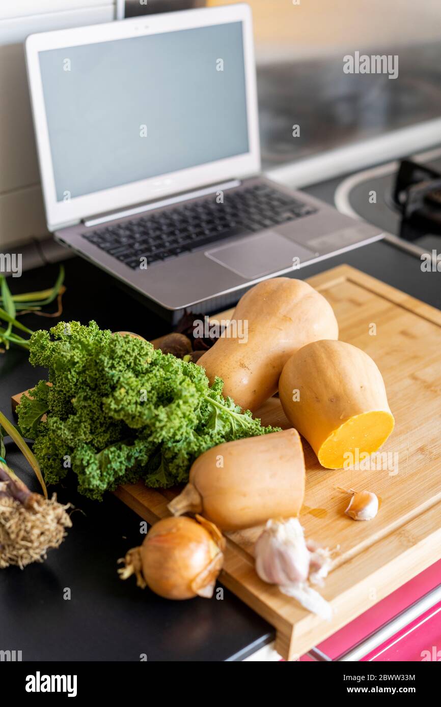 Verdure sane in cucina con computer portatile Foto Stock