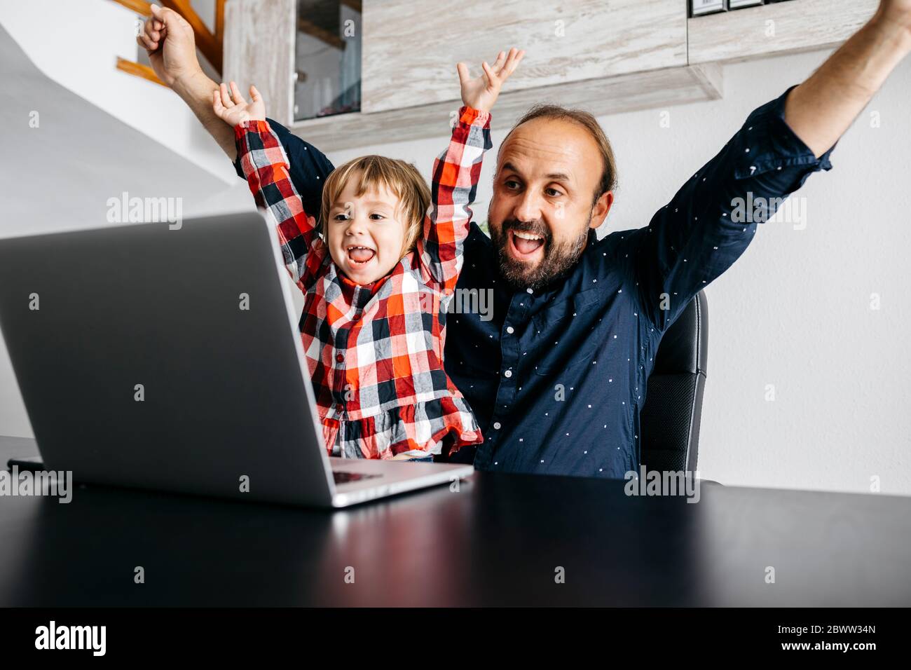 Felice padre con figlia che ha una video chat alla scrivania Foto Stock