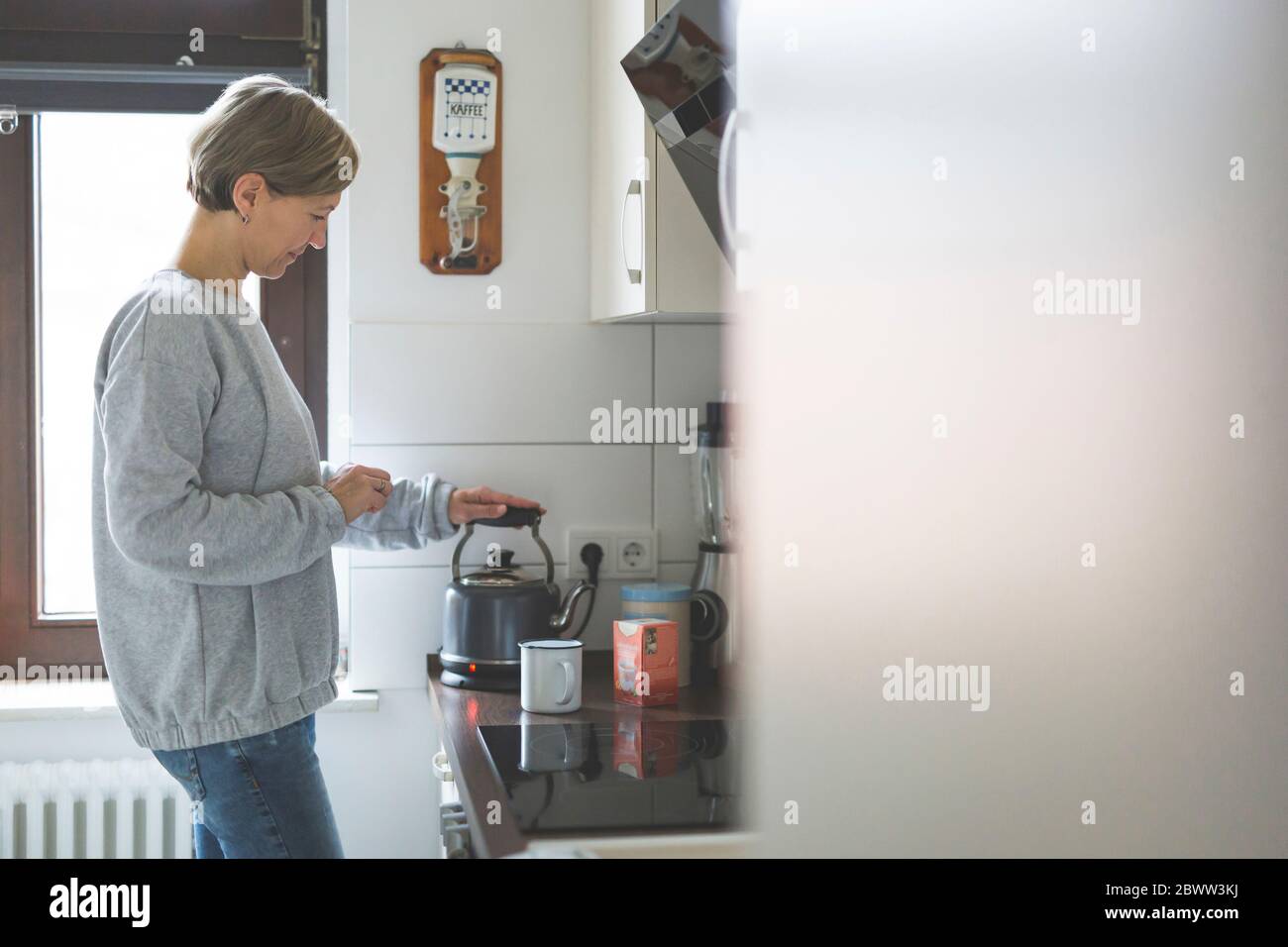 Donna matura che prepara il tè in cucina Foto Stock