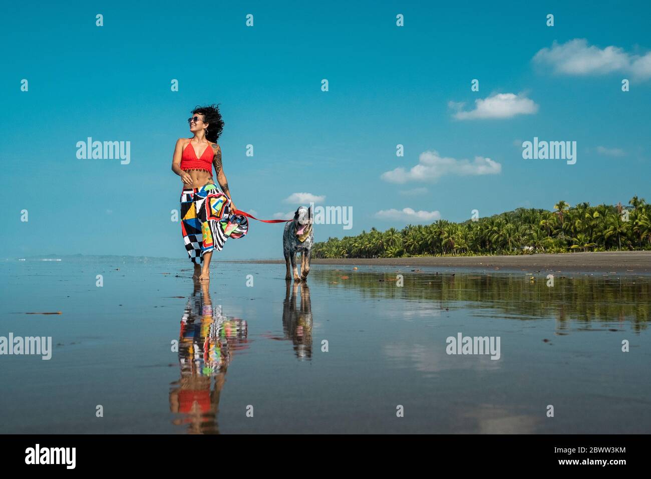 Giovane donna che prende il suo cane per una passeggiata sulla spiaggia, Costa Rica Foto Stock