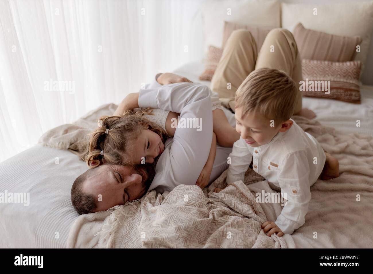 Padre che si stende a letto trascorrendo del tempo con i suoi due figli Foto Stock