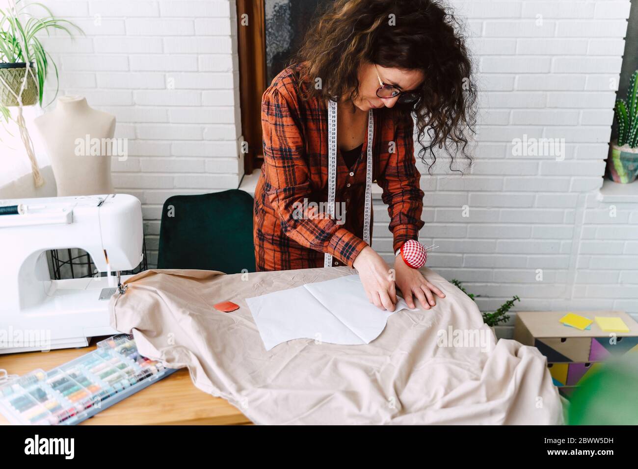 Donna che pinning modello di cucito sul tavolo a casa Foto Stock