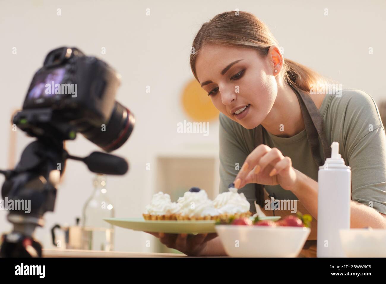 Blogger giovane che mostra il processo di decorazione delle torte cotte e di tiro sul video Foto Stock