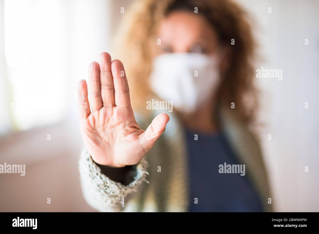 Donna con maschera che mostra palmo della mano, dicendo stop Foto Stock